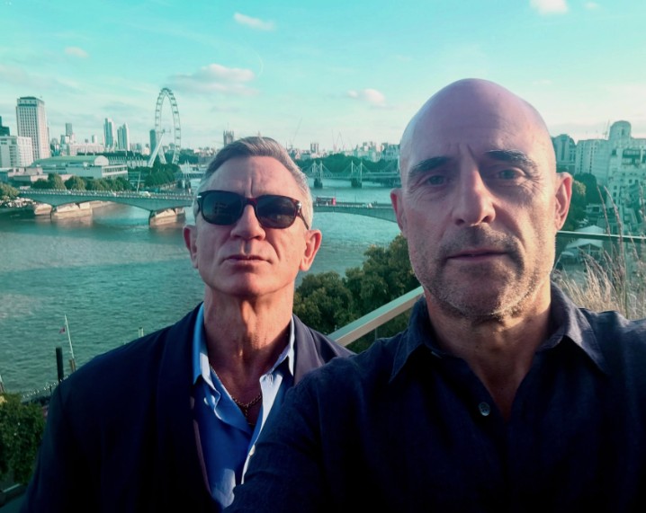 Mark Strong and Daniel Craig taking a photograph together overlooking London